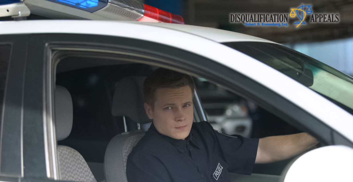 Young police officer seated in patrol car for NYPD age requirements